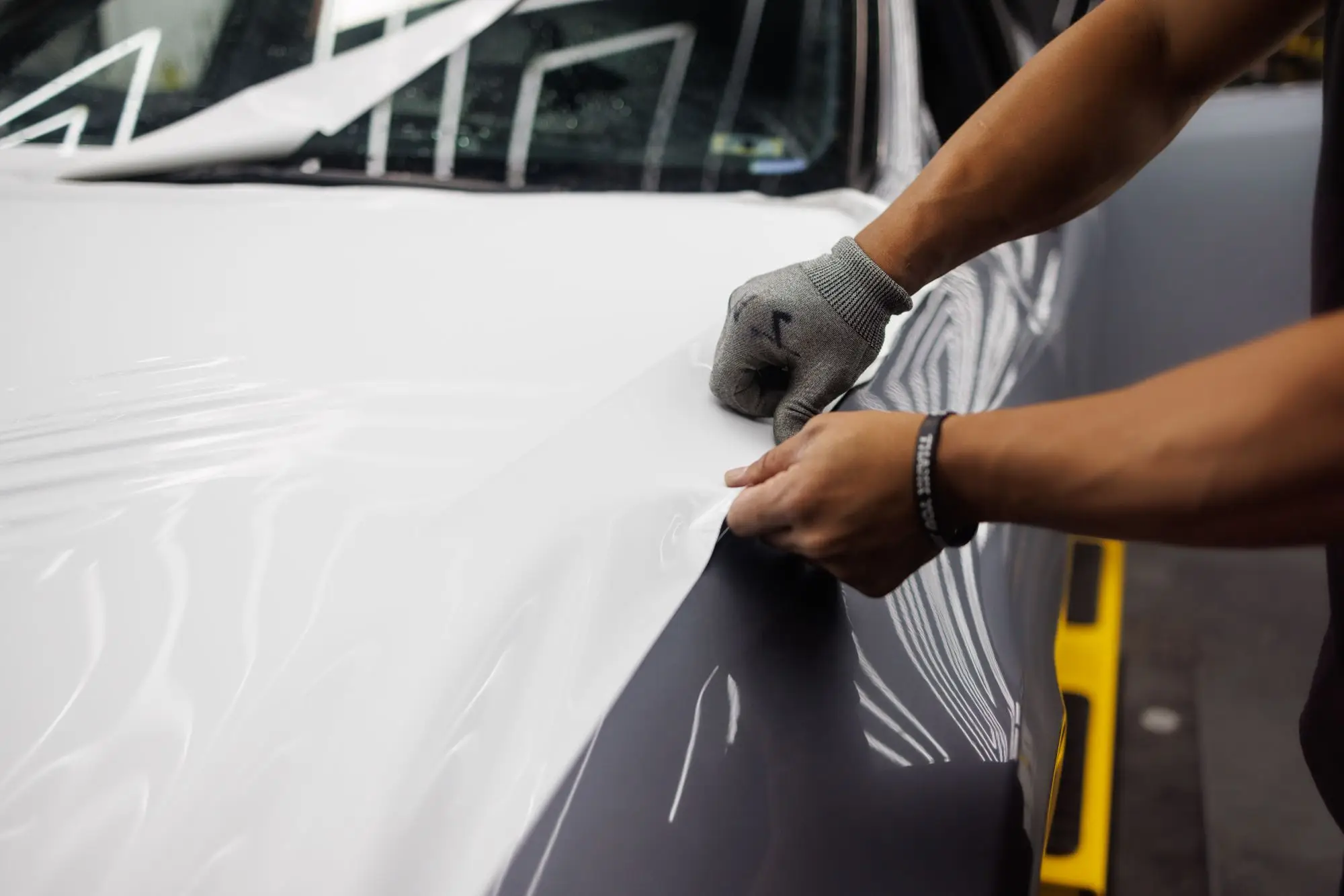 Dua tangan merapikan film pada panel mobil putih