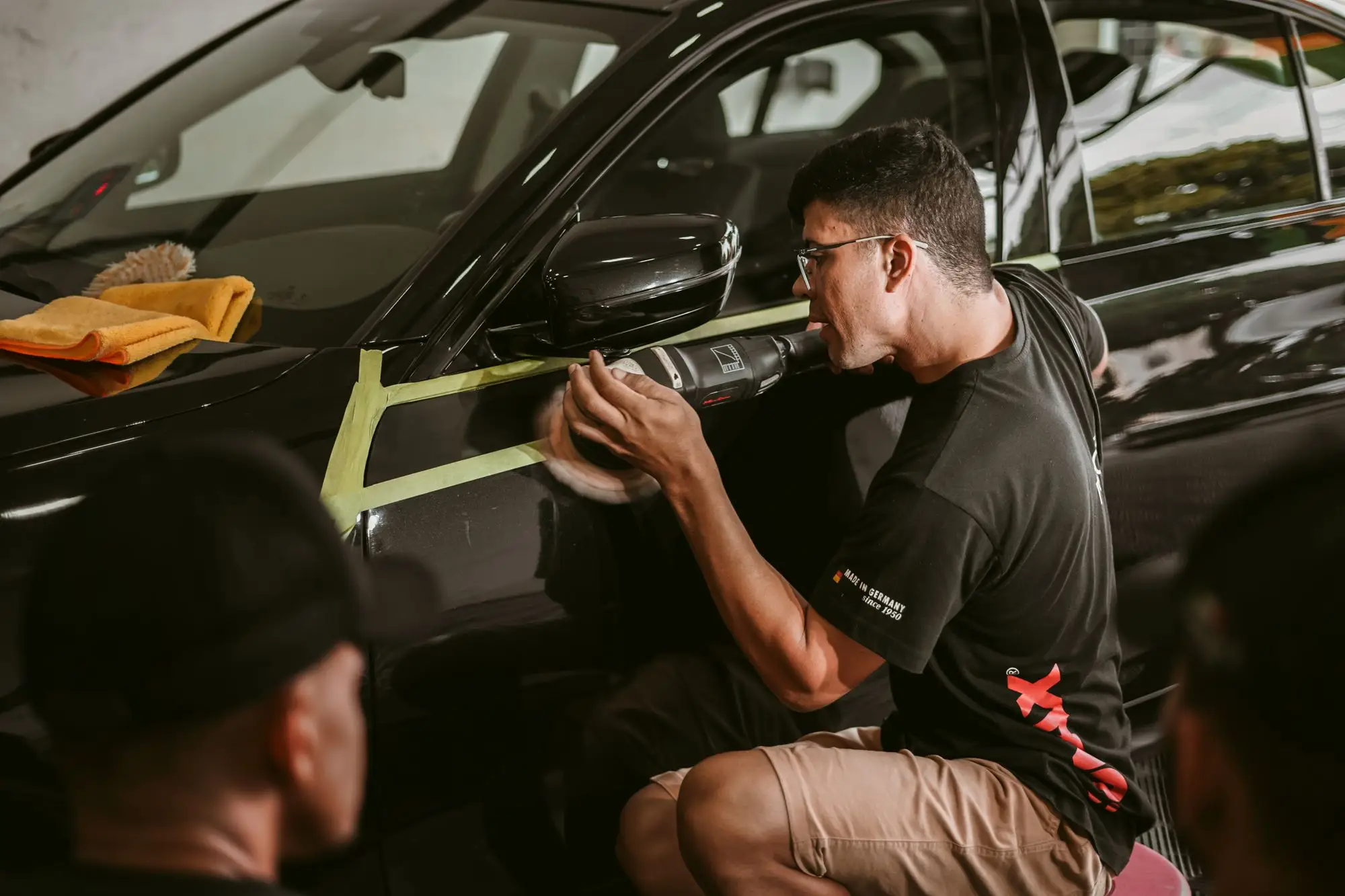 Teknisi memeriksa permukaan pintu mobil hitam sebelum pengerjaan